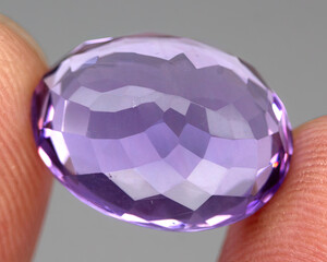 Natural gemstone purple amethyst on gray background