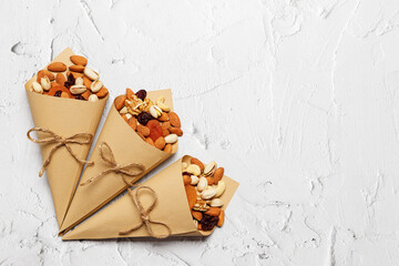 Mixed nuts and dried fruits in Retro Kraft Paper Cones on a light concrete background. Symbols of the Jewish holiday of Tu Bishvat Healthy snack - mix of organic nuts and dry fruits.