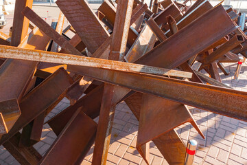 A huge bunch of iron anti-tank barriers lay down on the ground. Industrial. Stop. Terrorism. Empty. Rust. Armored. Battlefield. Row. Block. Nobody. Fight. Battle. Welded. Strong