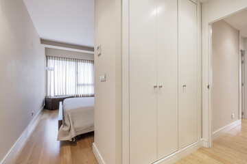 Bedroom with a double bed with a gray bedspread and a dresser with three white wooden doors