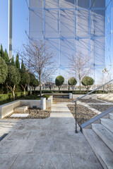Recreation area in the shade of an office building with hedges, trimmed trees and white stone stairs