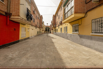 Fototapeta na wymiar Pedestrian street between buildings with brick facades and metal gates on the ground floors