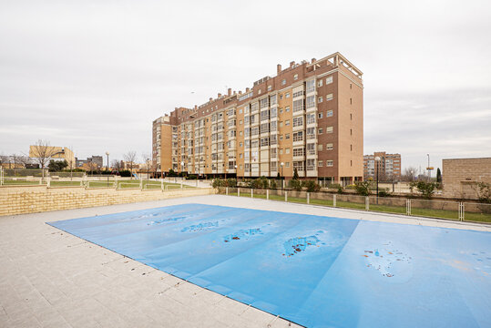 Fa&ccedil;ade of some buildings with a swimming pool complex covered with tarpaulins, squash courts, gardens and basketball and seven-a-side football courts