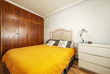 Bedroom with a double bed with a blue bedspread and a built-in wardrobe with old wooden doors and attics with trunks