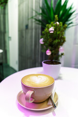 A cup of coffee on the table in a coffee shop. Cappuccino and various sweets were ordered by the restaurant's visitors. Interior design in a cafe. There are cups and Christmas tree on the white table