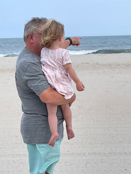 Beach Grandfather Pointing Granddaughter Looking