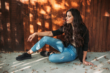 Portrait of a young brunette girl. Wooden background, fall vibes