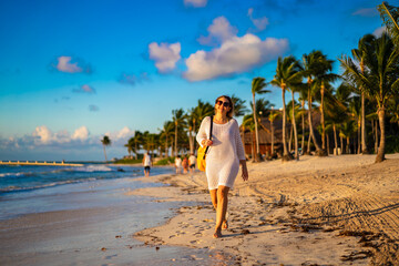 Obraz premium Beach holiday - woman walking on sunny, tropical beach in the morning