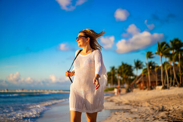Beach holiday - woman walking on sunny, tropical beach in the morning 

