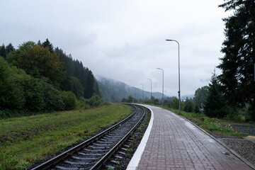 Railway station platform. Railroad leading to the mountains. Cloudy weather at the station. Street...