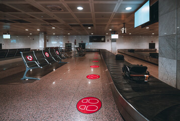 An empty baggage claim zone of a modern airport terminal with rows of seats and different luggage...
