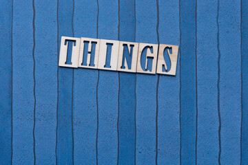 the word "things" in stencil type on blue paper with stripes