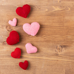 Multicolored pink knitted hearts on a wooden background. Happy Valentine's Day, Mother's Day and birthday greeting card.