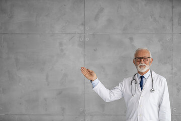 Senior doctor pointing away on free space for your advertising content