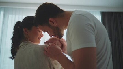 Close-up shot of young parents expressing unconditional love for their baby. Mother holding baby in arms while father kissing in slow-motion