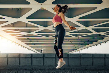 Fitness woman jumping rope before training outdoors