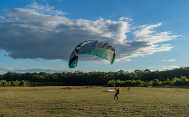 Learn to paraglider, paraglider catching wind flow from the ground in summer warm weather with blue...