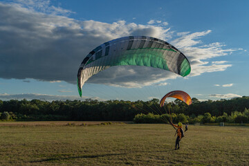 Learn to paraglider, paraglider catching wind flow from the ground in summer warm weather with blue sky and white clouds background	