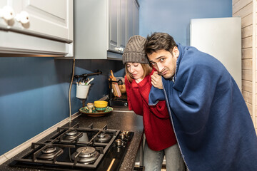 Freezing couple warming close to gas oven. Cold winter and high price taxes concept