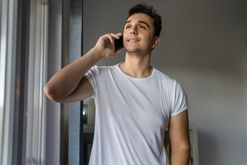 One man caucasian male standing by the window using mobile phone talk
