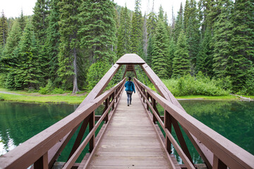 Rear view female hiker crossing Rainbow Bridge at Lightning Lake, B.C.