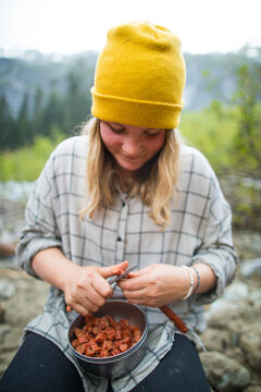 Young woman preps food while camping in the backcountry.