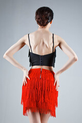 An elegant dancer performs a Latin American dance in an elegant red dress with sparkling jewelry....