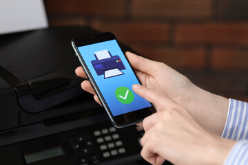 Man using printer management application on mobile phone indoors, closeup. Image on device screen.
