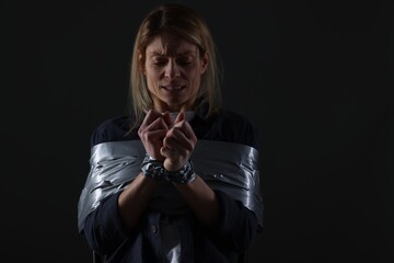 Woman taped up and taken hostage on dark background