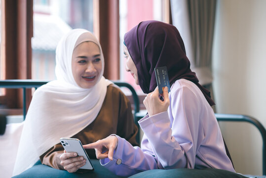 Two young muslim women shopping online via smartphone system Pay by credit card online