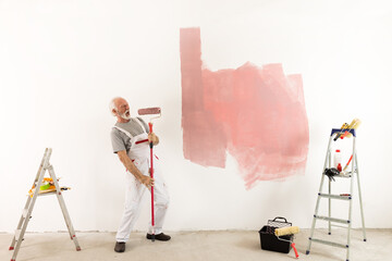 Senior man singing during painting wall