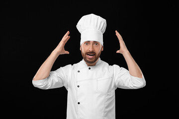 Emotional mature male chef on black background