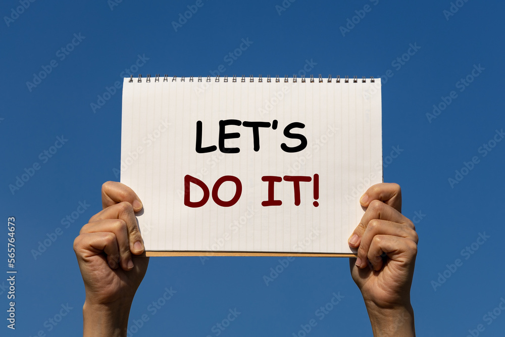 Poster let's do it placard. this text is on notebook paper which is held by 2 hands with blue sky as backgr