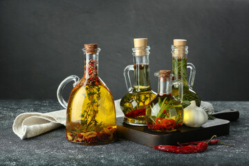 Cooking oil with different spices and herbs in jugs on light grey table
