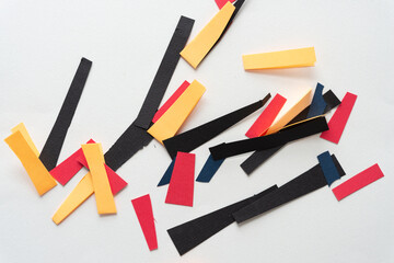 short paper stripes in black, red, and yellow scattered on a white background