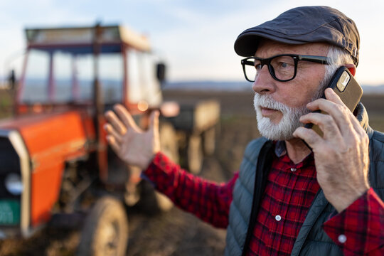 Angry farmer talking on mobile phone in field