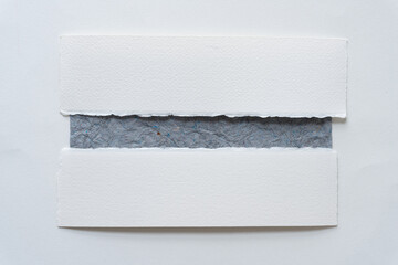 two paper stripes with deckle and torn edges over textured gray paper