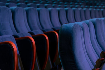 Empty upholstered chairs in a concert hall or cinema, side view, dark tone.