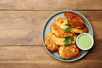 Tasty parsnip cutlets with parsley and sauce on wooden table, top view. Space for text - obrazy, fototapety, plakaty