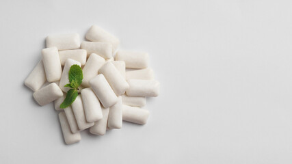 Tasty chewing gums and mint leaves on white background, flat lay. Space for text