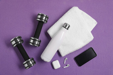 Flat lay composition with stylish thermo bottle and dumbbells on purple textured background