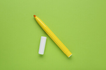 Bright yellow marker and cap on light green background, flat lay