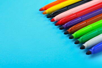 Many different colorful markers on light blue background, closeup. Space for text