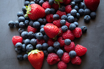 Blueberries, raspberries and strawberries on black background 