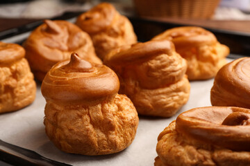 Delicious fresh profiteroles on baking pan, closeup