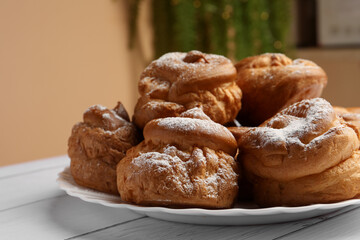 Delicious profiteroles with powdered sugar on white wooden table