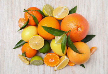 Different citrus fruits with fresh leaves on white wooden table, flat lay