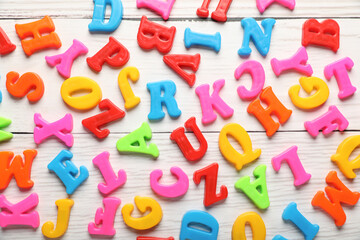Fototapeta premium Colorful magnetic letters on white wooden table, flat lay