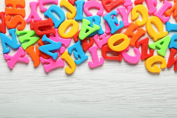 Colorful magnetic letters on white wooden table, flat lay. Space for text