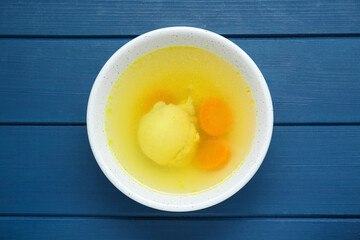 Delicious chicken bouillon with carrot on blue wooden table, top view